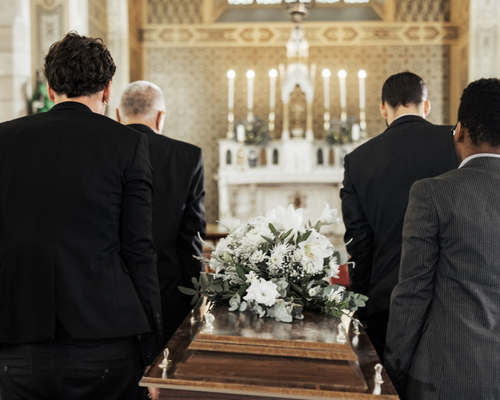 Four pallbearers carrying a casket through a church.