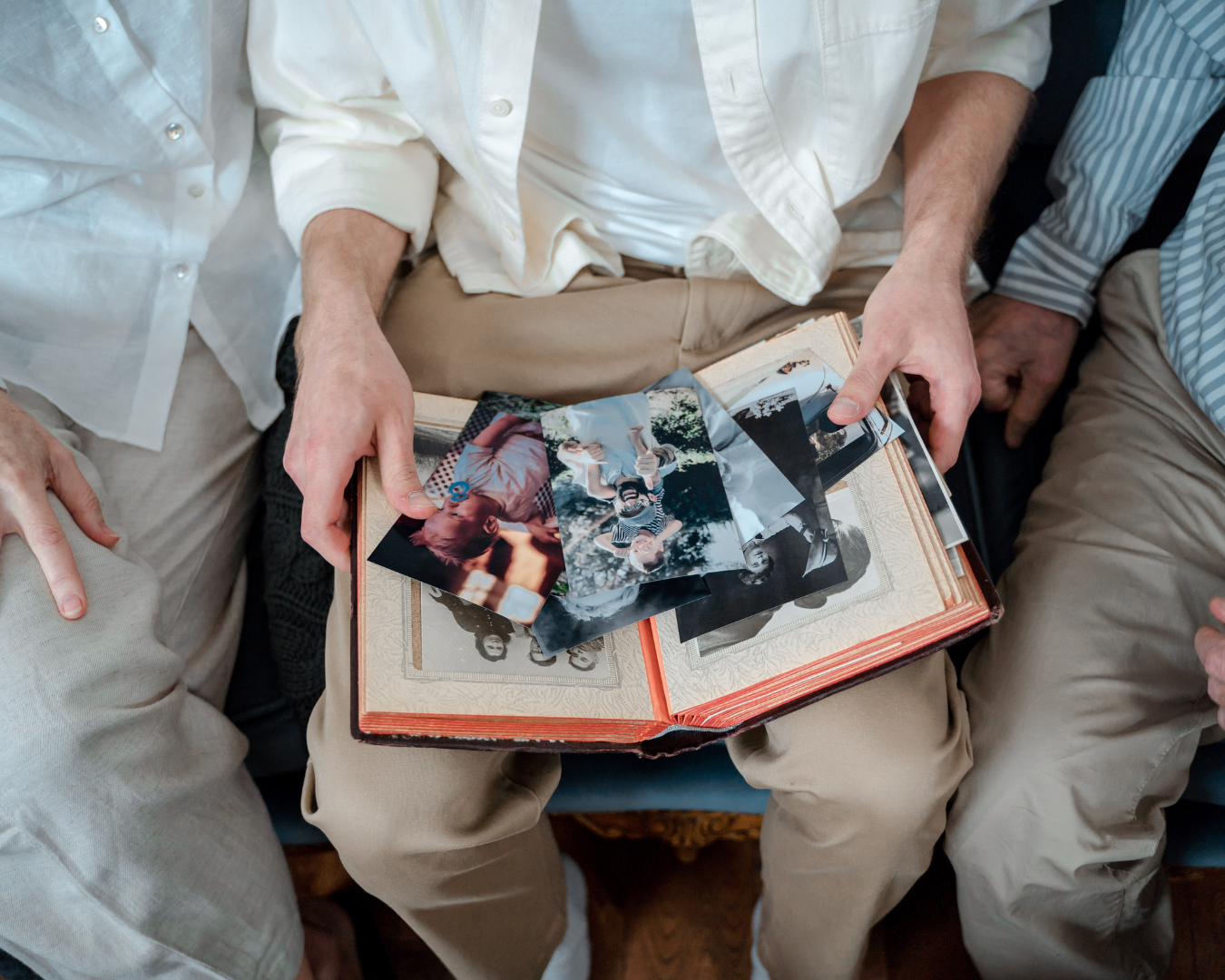 Three people gathered around a memorial book, looking at photos and remembering a loved one.