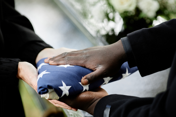 A folded American flag being respectfully handed to a family member during a military funeral ceremony, symbolizing honor and gratitude for a veteran’s service.